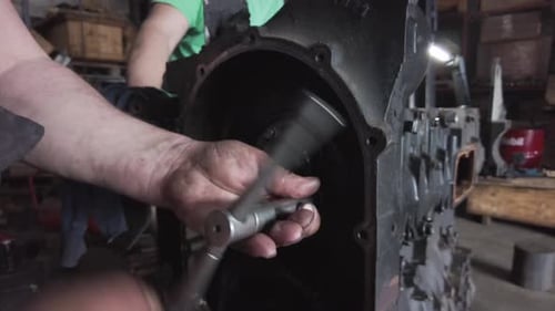 Mechanic Repairs Large Engine with Socket Wrench