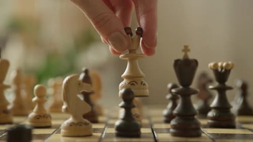 Hand Moving Chess Queen on Wooden Chessboard