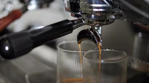 Espresso machine pouring hot drink into glass cups
