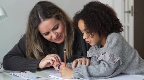 Caring Woman Helping Young Girl With Homework