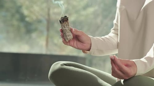 Woman Meditating with Burning Sage Indoors