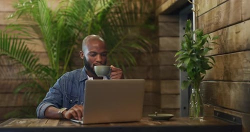 4k video footage of a young man having coffee and using a laptop at a cafe
