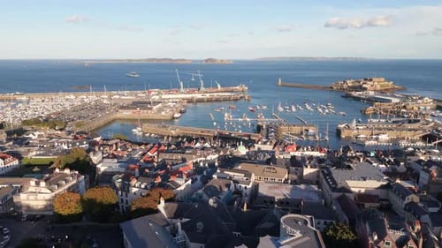 High flight over rooftops of St Peter Port Guernsey towards harbour Herm Sark and Jethou in the