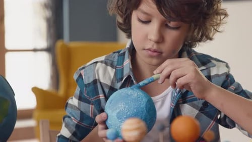 Creative young boy paints blue planet earth exploring space travel dream