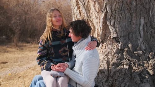 Young couple romantically enjoys spring date, woman strokes man hair lovingly.