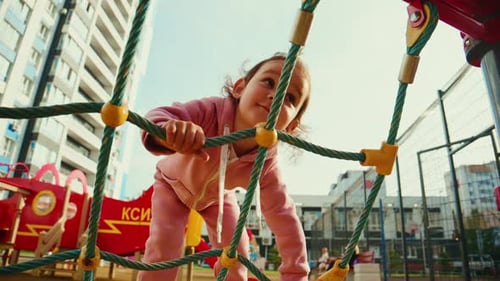 Ein kleines Kind klettert auf eine farbenfrohe Spielplatzstruktur und genießt die Spielzeit an einem strahlend sonnigen Tag in einem
