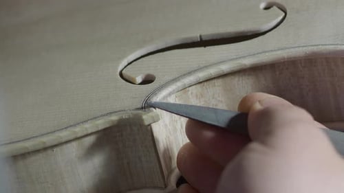close up of artisan luthier maker work on new classic handmade raw violin smooth edge in waist and p