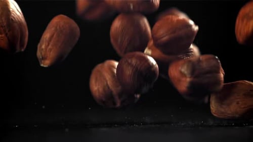 Hazelnuts Falling on Dark Surface in Slow Motion