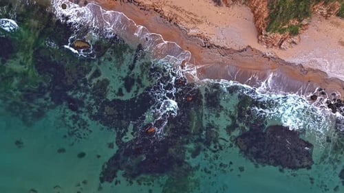 Breathtaking aerial view of rocky coastline meeting sandy beach