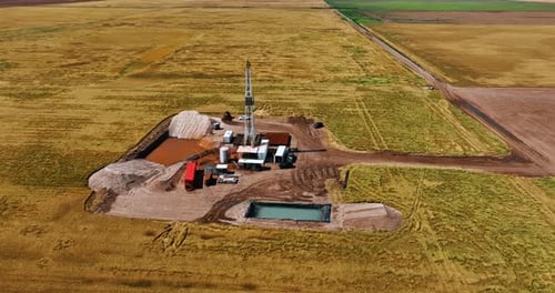 Flight around the small site for natural resources drilling in the vast field.