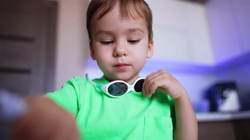 Lovely Caucasian toddler chewing his food. Little baby boy eating himself in the kitchen. Close up.