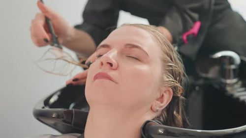 Woman relaxing while hair stylist applies color in salon