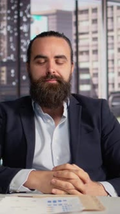 Bearded man in suit speaks in office