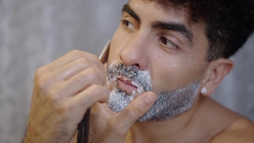 Handsome Guy Shaving with a Razor at Home