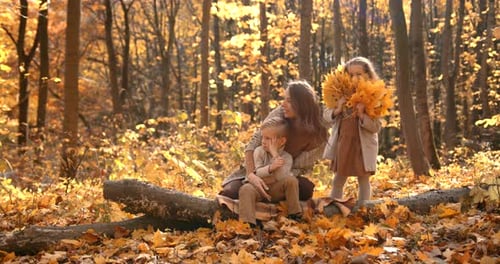 Beautiful Mother with School Kids in the Autumn Forest