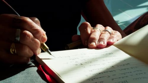 Extreme close-up of a senior elderly woman lady hand writing on a paper notebook with a fountain