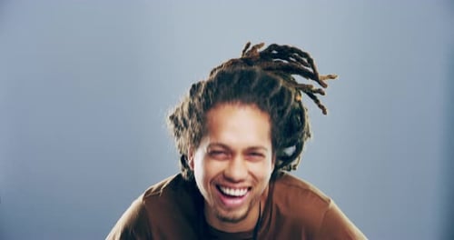 4k video footage of a young man laughing against a grey studio background