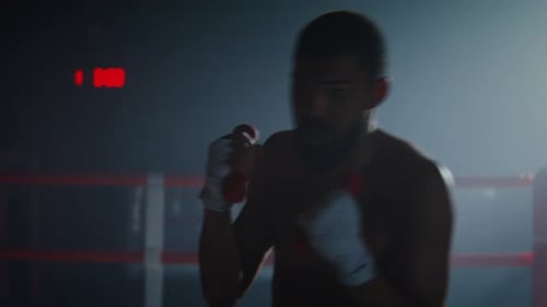 Young Adult Man Boxing in Dimly Lit Ring