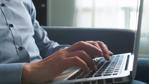 Man Works on a Laptop While Sitting on the Couch at Home