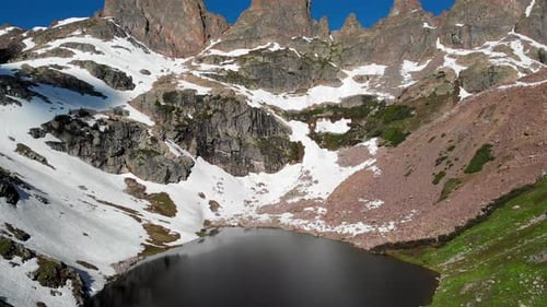 Backwards dolly over beautiful lake surrounded by mountains. Aerial.