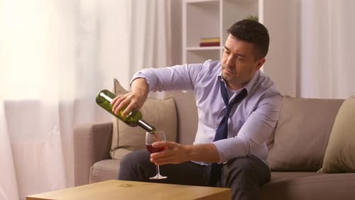 Man Pours and Drinks Red Wine at Home