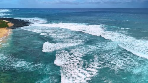 Ocean waves roll to the shore. Aerial view on the waterscape of the Pacific Ocean on a windy day.