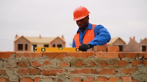 Bricklayer Using Level Tool at Construction Site