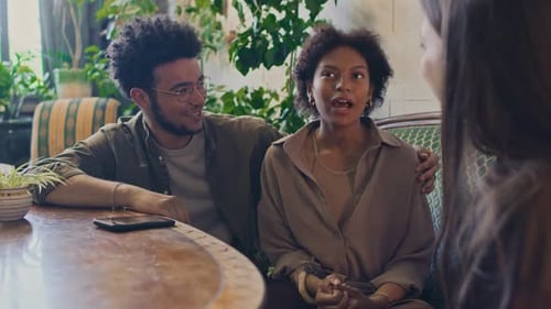Jeune femme biraciale partageant une histoire drôle avec des amis au café