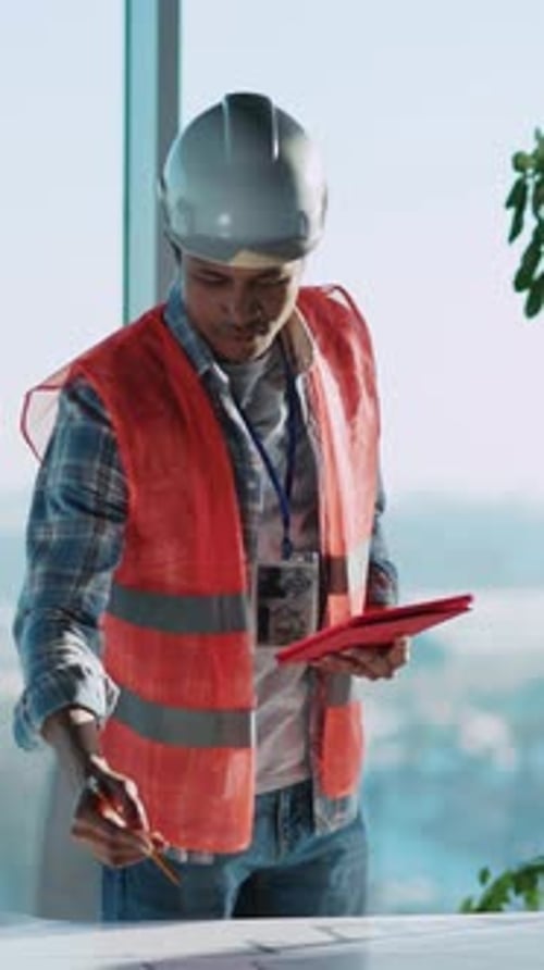 African American Young Foreman Builder in Safety Vest Working Inside Office Architect Male Designing