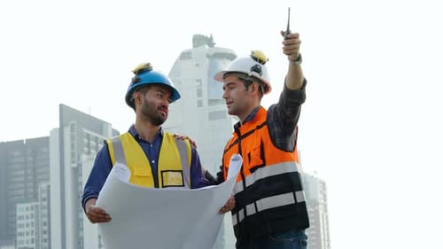 Zwei Bauingenieure überprüfen die Informationen aus dem Bauplan in Teamarbeit, Projektleiter planen