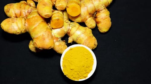 Fresh Raw Turmeric with Powder Close-Up on black Background studio shot