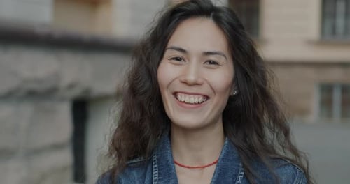 Câmera lenta de uma alegre mulher asiática rindo, sentindo-se feliz e animada em pé na City Street