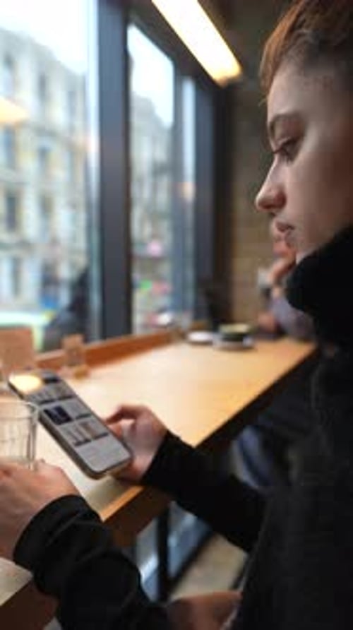 Close Up Portrait of Young Beautiful Girl Drinking Coffee with Smartphone in Hands
