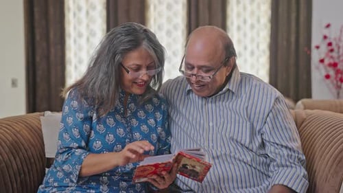 Pareja india de ancianos discutiendo viejos recuerdos mientras revisan un álbum de fotos