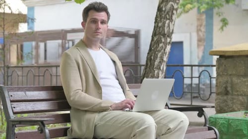 Man Works on Laptop in Urban Park Setting
