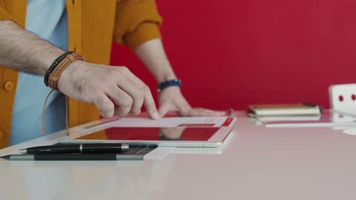 Hand eines unkenntlichen Mannes surft im Büro online auf dem Tablet