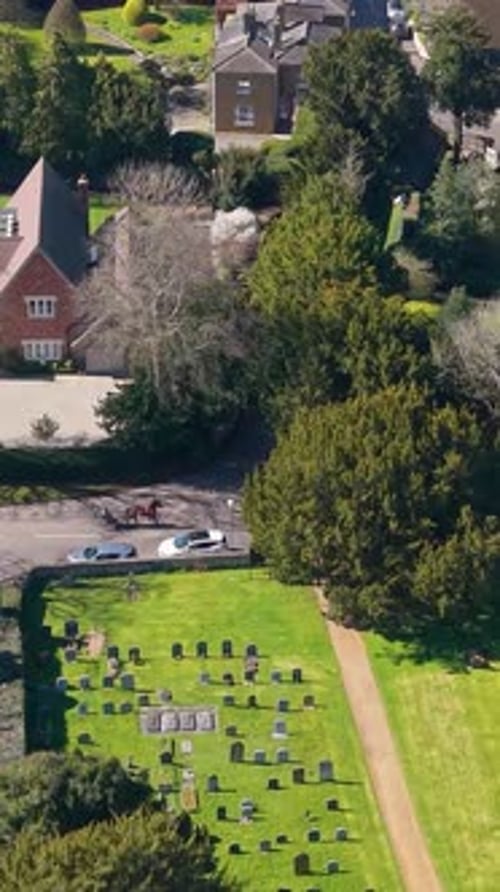 Vertical drone flight over Hertingfordbury village as pony and trap crosses Hertingfordbury road, UK