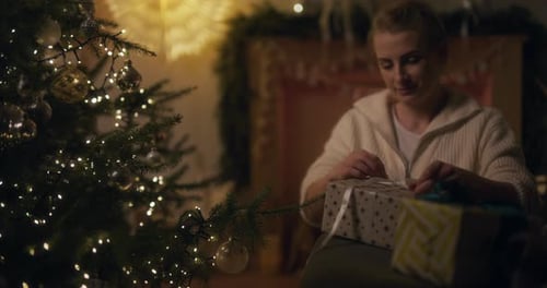 Woman Tying Ribbon Around Christmas Present
