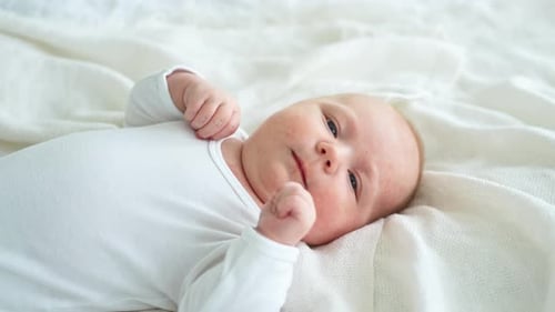 Peaceful Infant Lying on White Blanket