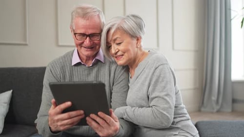 Smiling Senior Couple Using Tablet on Couch