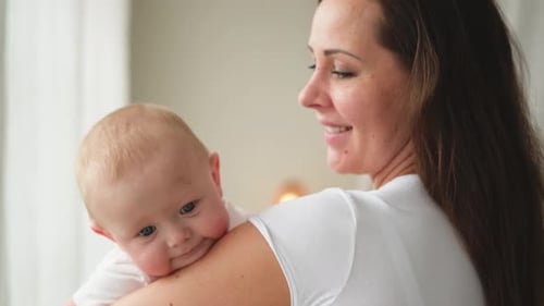 Loving Mother Holding Adorable Baby Indoors