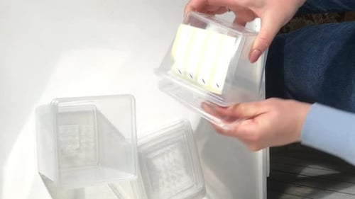 Récipients en plastique pour congeler et conserver les aliments. Une femme passe en revue un achat. Vidéo verticale.