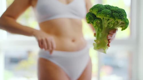 Una mujer sostiene un brócoli en la mano: concepto de alimentación y digestión saludables