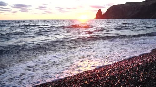Kleine Meereswelle, verschwommene, weiche, schaumige Wellen, die den goldenen Sandstrand bei Sonnenuntergang waschen