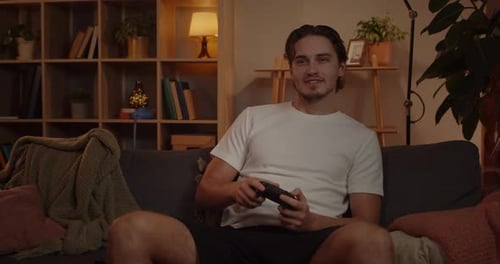 Front View of Excited Caucasian Guy Playing Video Game and Using Joystick