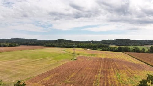 Aerial view of rural farm fields and crops on a beautiful blue sky summer day with green trees.