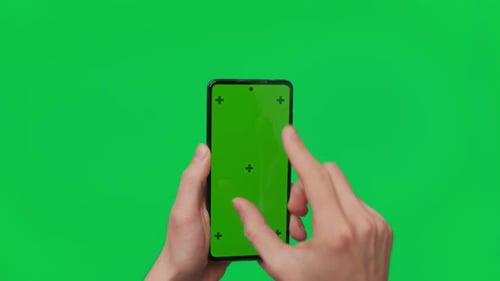 Male Hand Holding a Smartphone with Vertical Green Chroma Key Screen Isolated on Green Mobile Phone