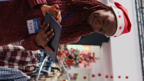 Woman In Santa Hat Using Tablet at Christmas Party