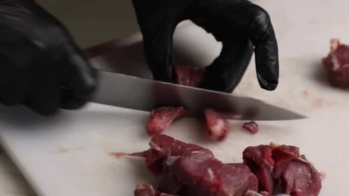 Chef Dicing Raw Meat on a Cutting Board