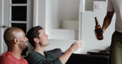 Three Young Men Toasting Beer Bottles on Couch